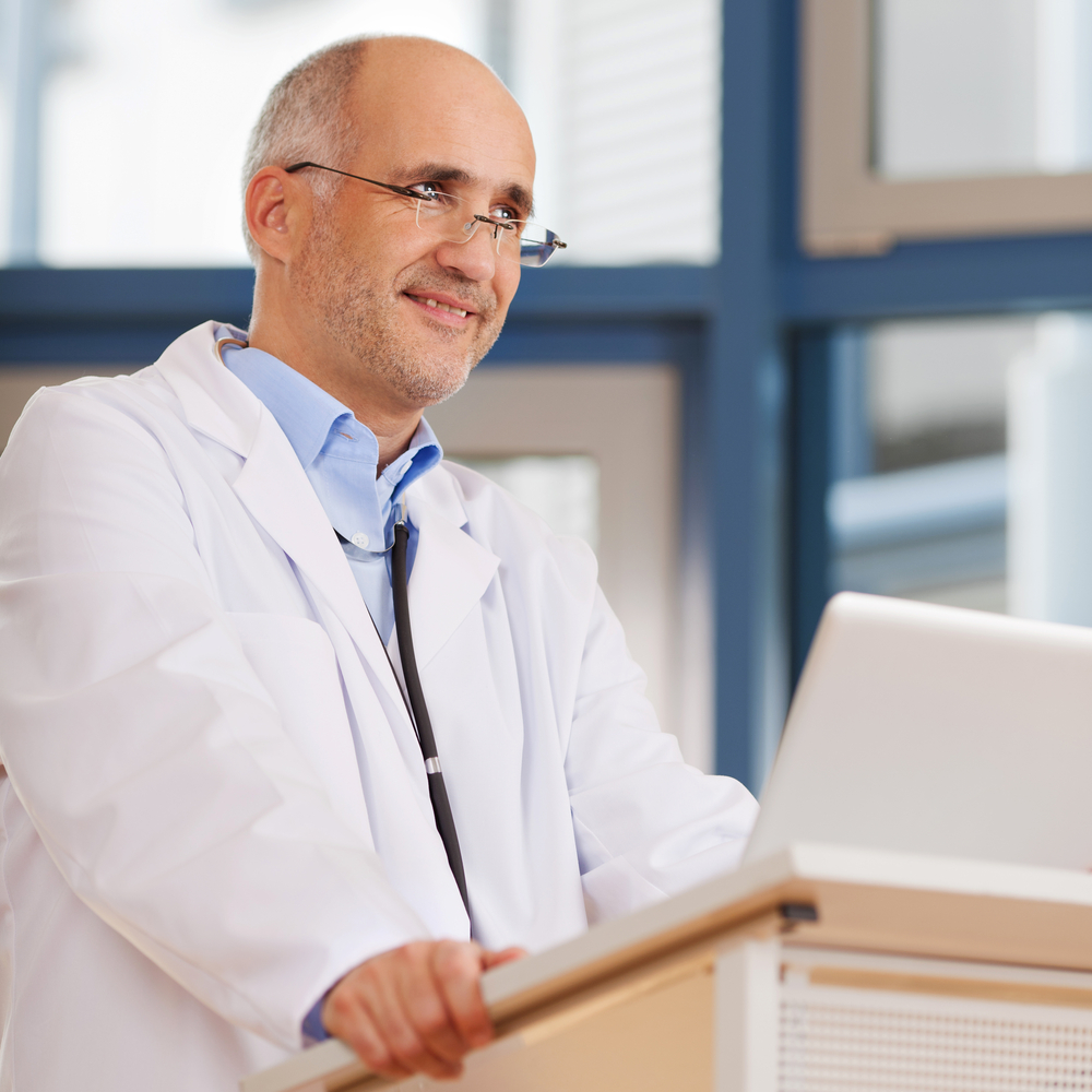 Confident male doctor looking away while standing at podium